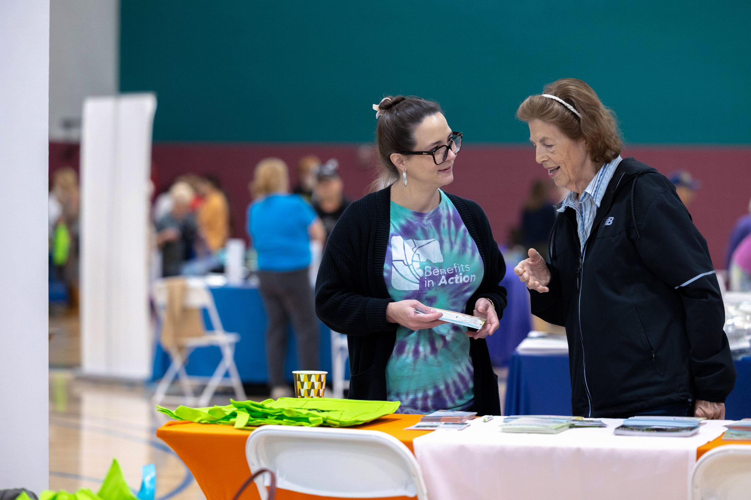 A Benefits In Action staff member speaks with a senior citizen at a resource fair